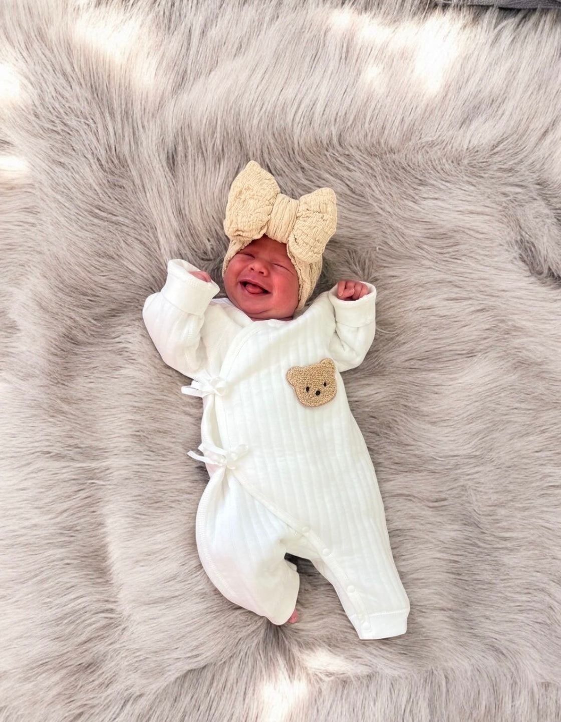 Soft touch unisex baby romper with side tie fastening and boucle teddy face.