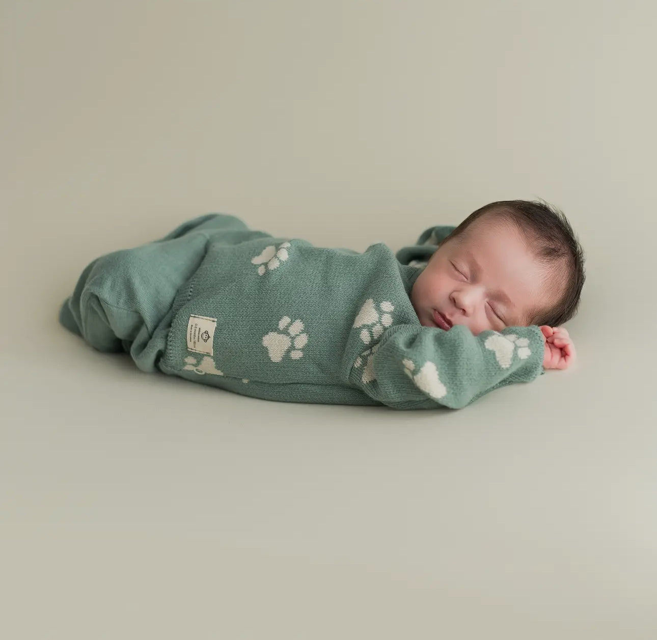 Sleeping baby lying on their stomach wearing the Little Paws organic sage green outfit.