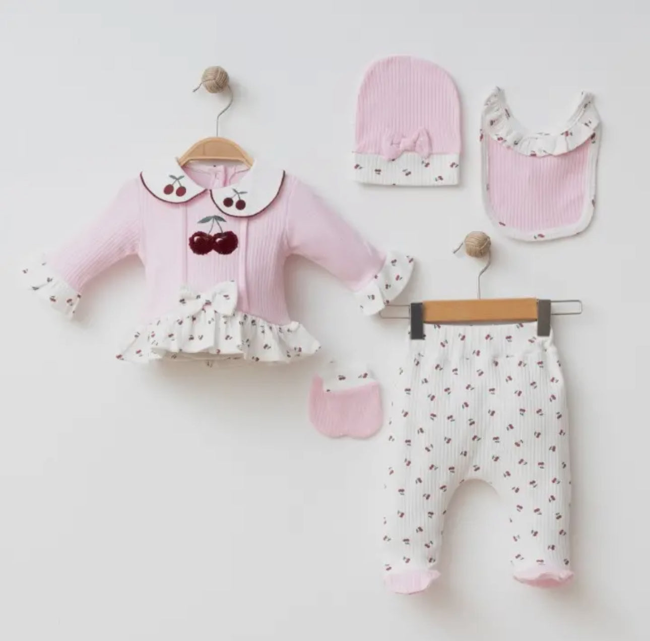Flat lay of the 5-piece Cherry Blossom baby set in soft pink and white with cherry patterns, including a collared top, pants, and matching accessories.