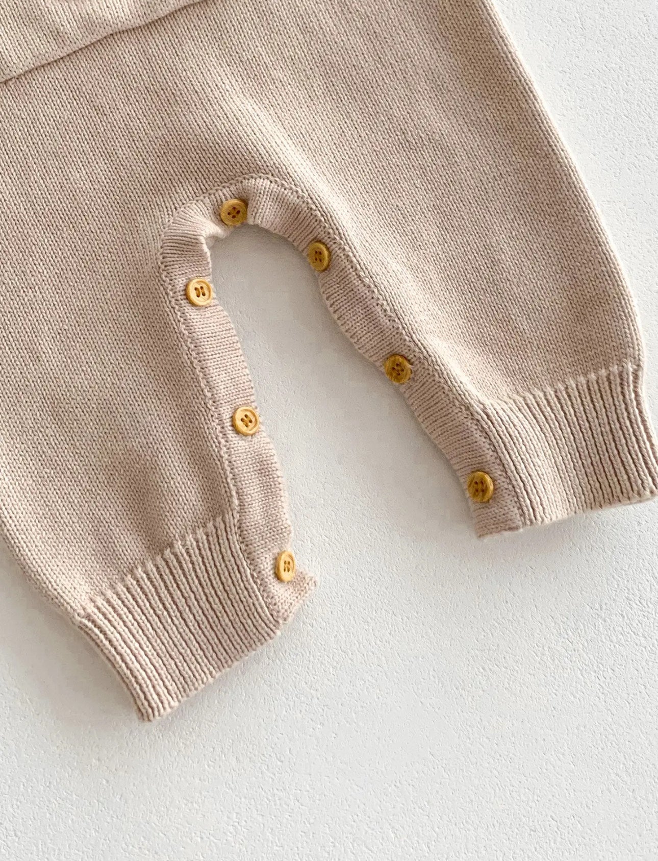 Close-up of the button fastening on the beige Cosi Bear Pocket Onesie legs