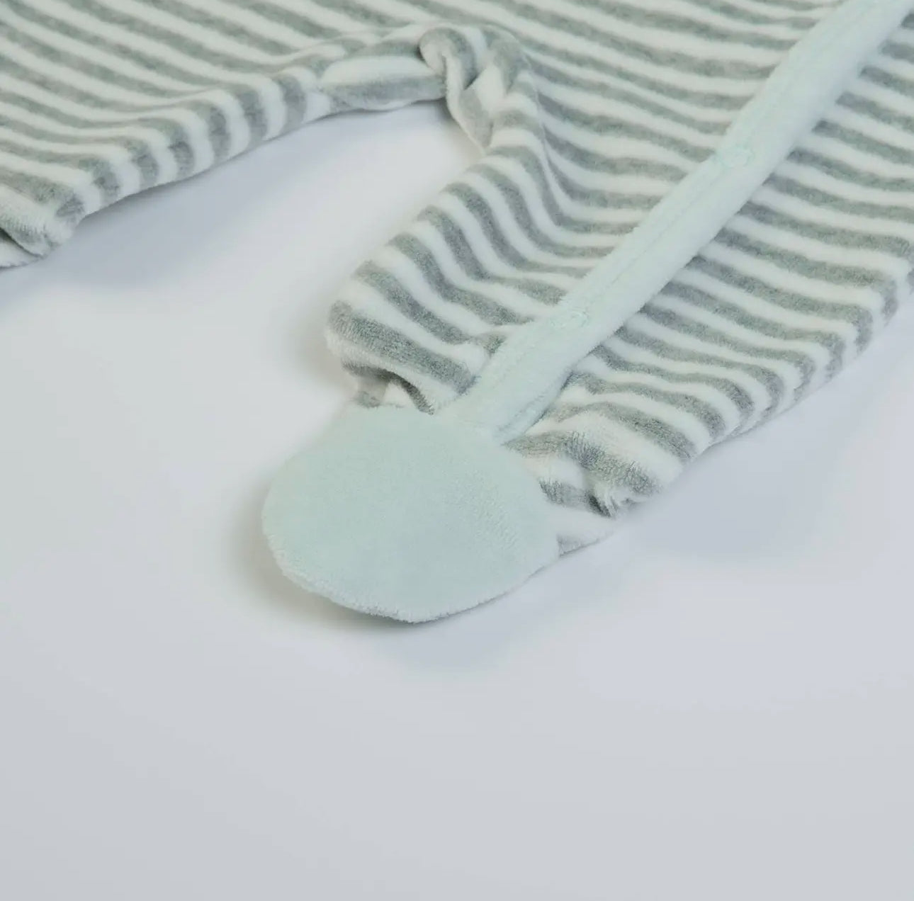 Close-up of the footed leg on a mint and grey velour baby grow, showing soft striped fabric