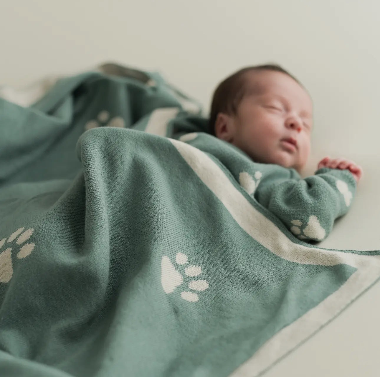 Little Paws Organic Cotton Blanket, baby laying on a flat surface 