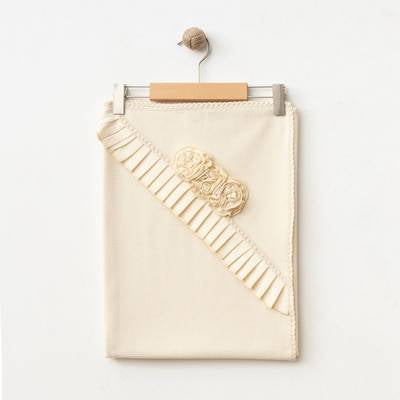 The Rosalie Blossom Blanket neatly folded on a hanger, highlighting its soft, breathable cotton fabric.
