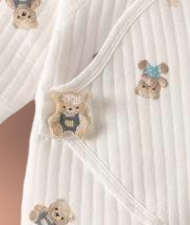 Close-up of the teddy bear and star print on the cream baby romper, showing soft ribbed cotton fabric